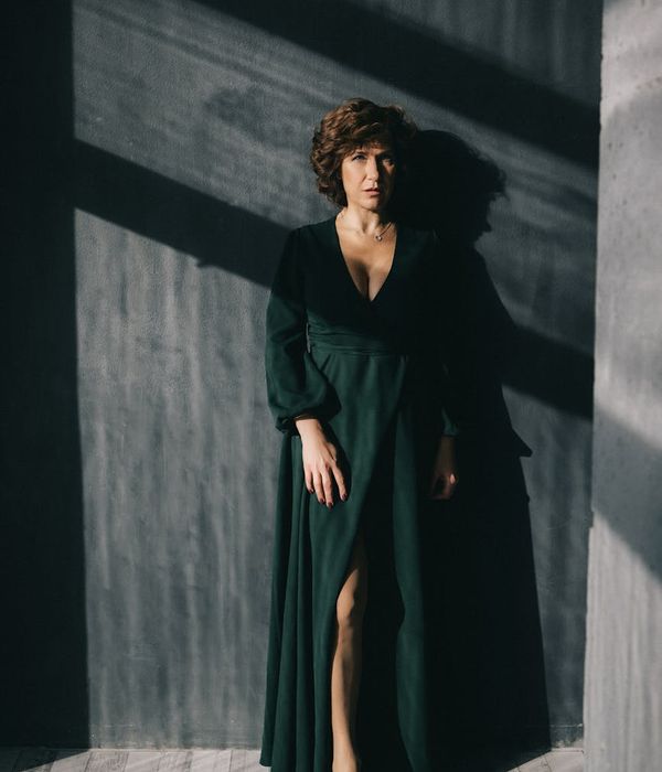 Woman in a calm, focused pose performing a low-impact exercise in a minimalist studio.